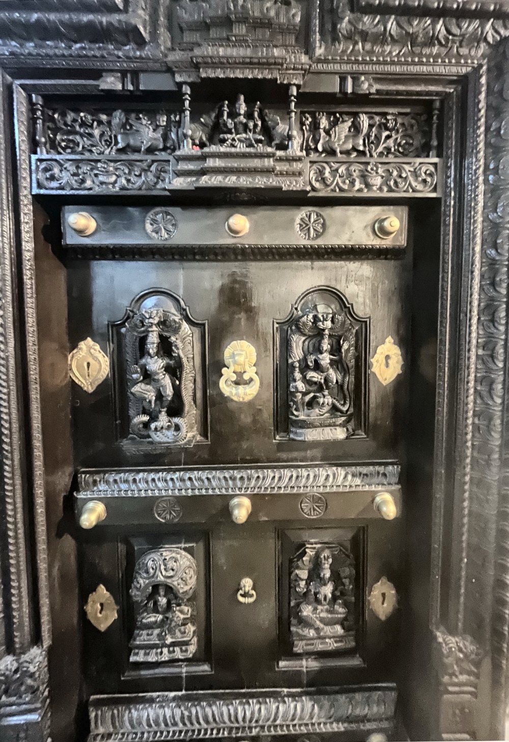 Carved crown and deity panels of an antique teak temple door