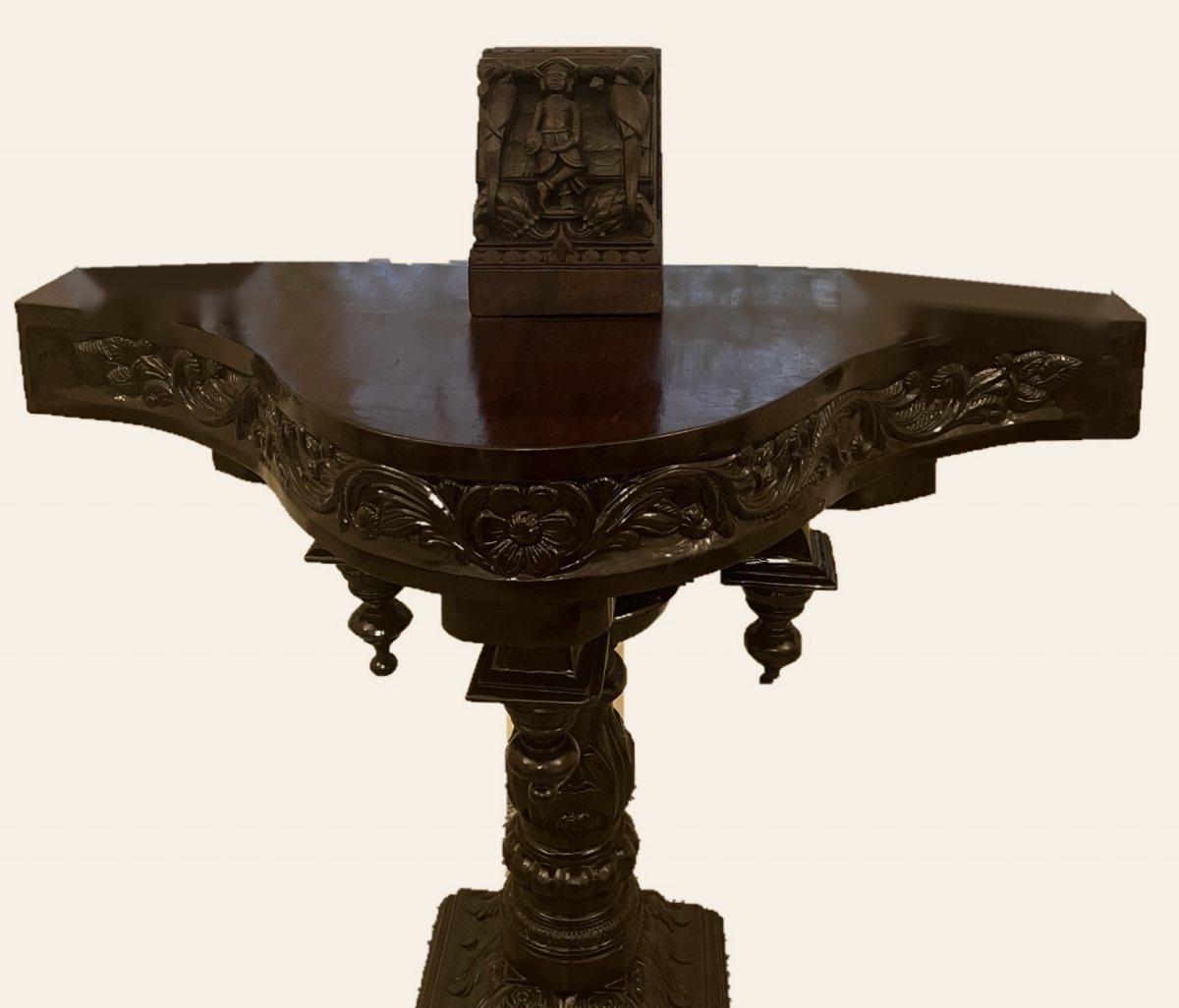 Antique carved teak panel of a young soldier on a carved teak console table